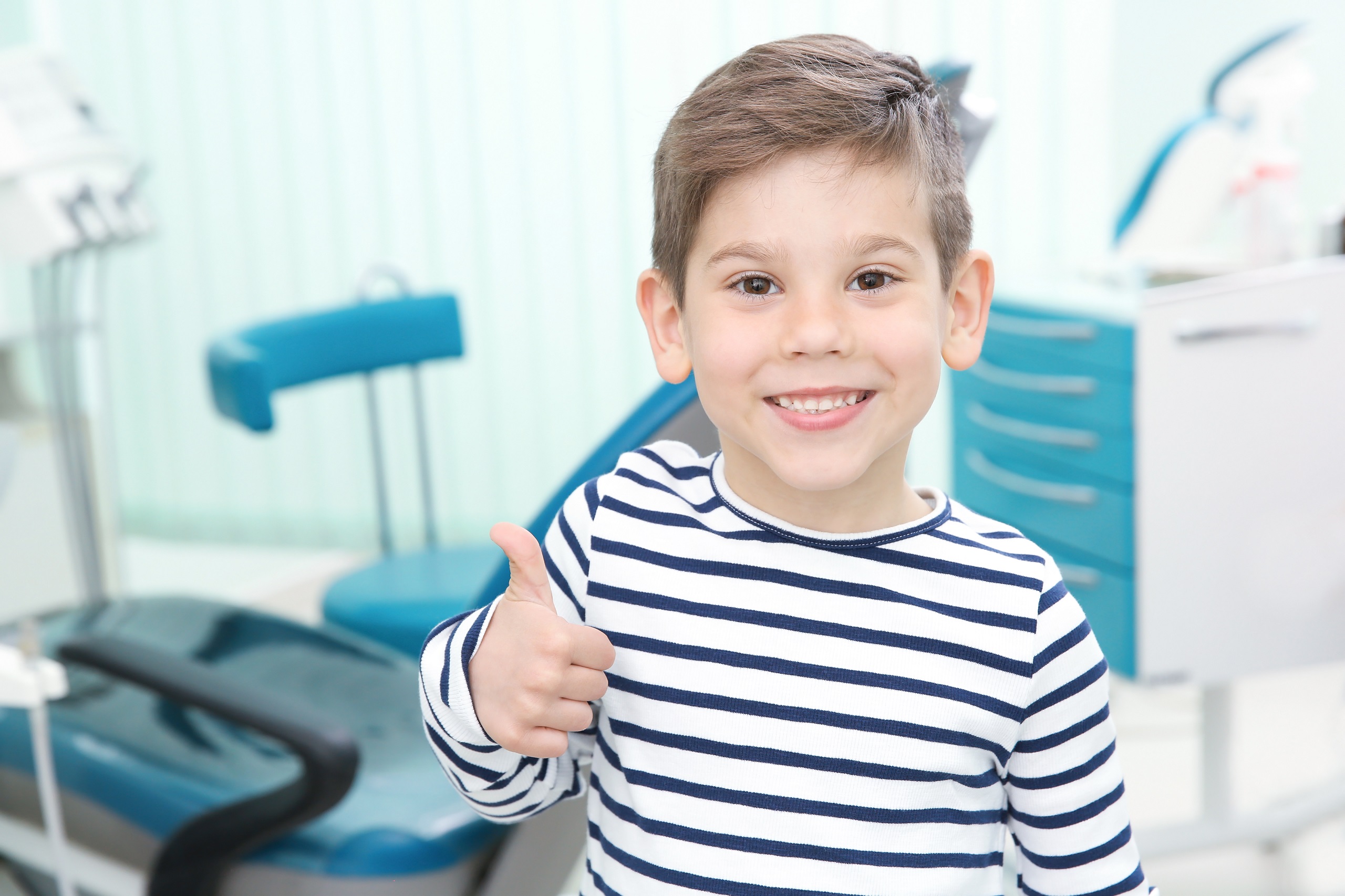 歯科医院の診察室で親指を立てて笑っている男の子