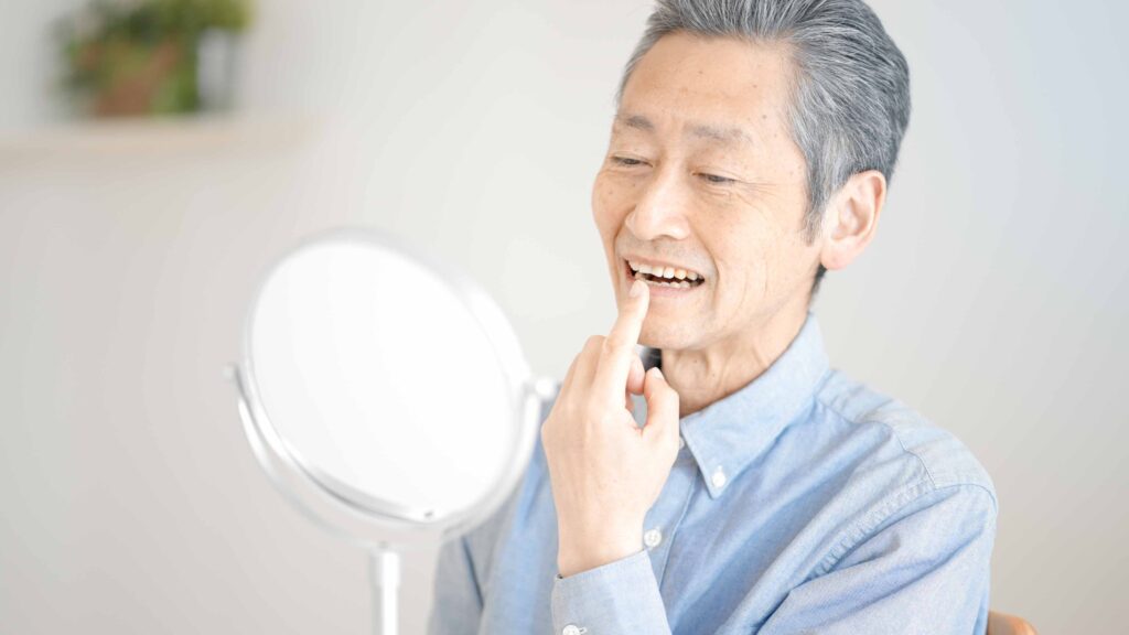 鏡で歯を確認する高齢男性